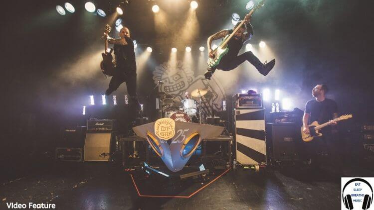 Members of punk band MXPX jumping on stage in the air