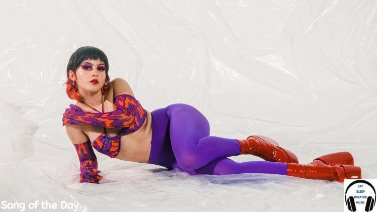 Music artist Neoma laying on a white floor wearing purple stockings and a crop top | Eat Sleep Breathe Music
